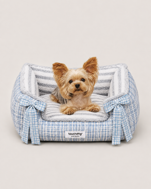 Small dog resting in blue tweed pet bed with plush interior and bow details