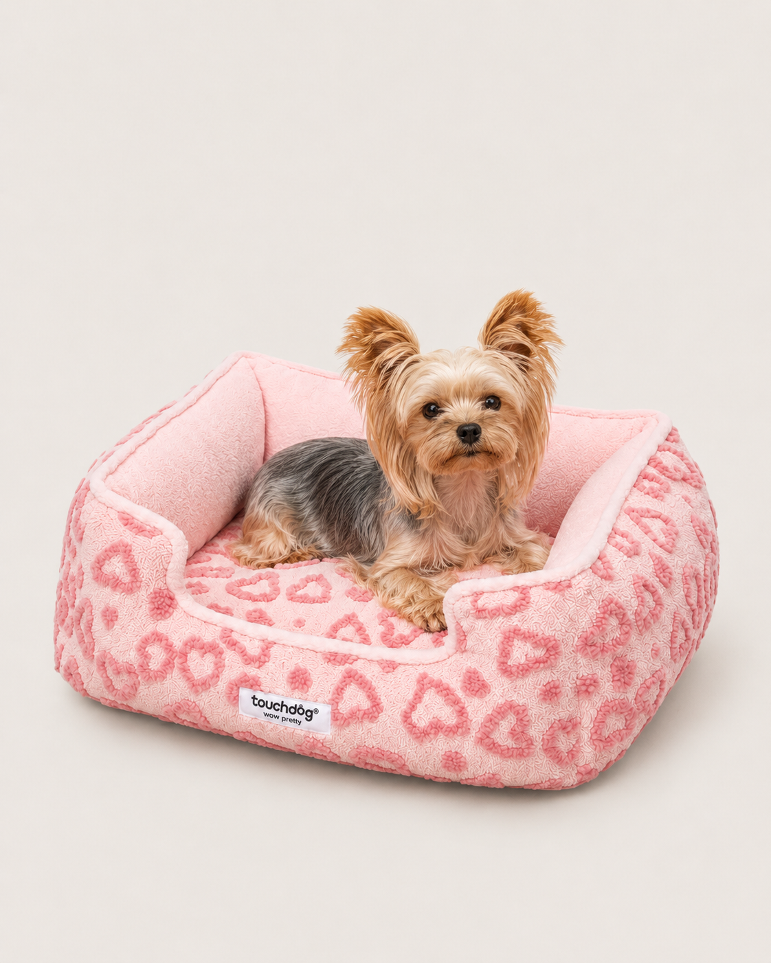 Small dog resting in pink heart plush pet bed